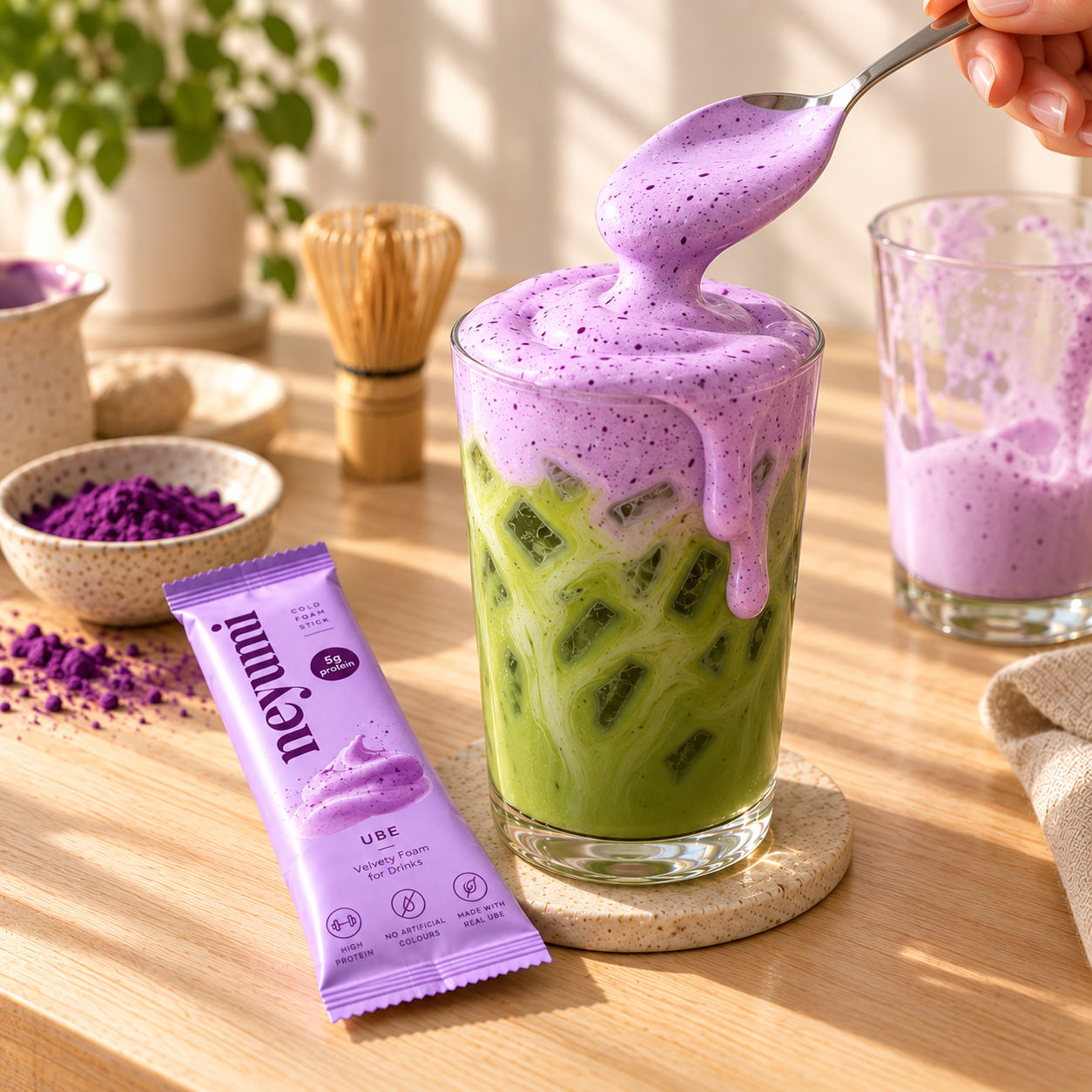Spooning purple cold foam onto iced matcha